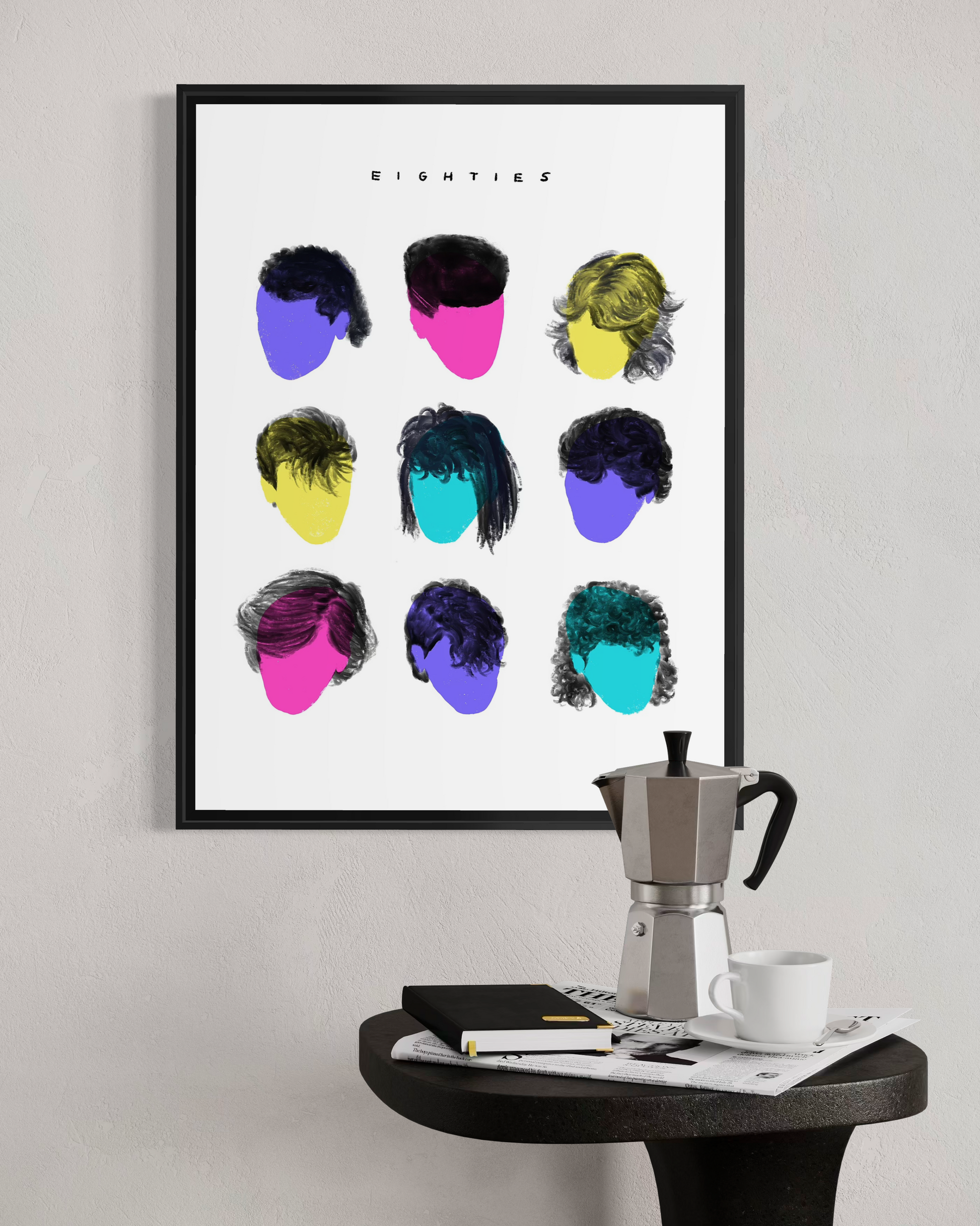 Vaykay-Idanshani Eighties Series framed print in a modern industrial interior. The bold 3x3 grid of retro hairstyle shapes is displayed above a dark concrete counter featuring a stack of design books and a vintage Moka espresso pot.